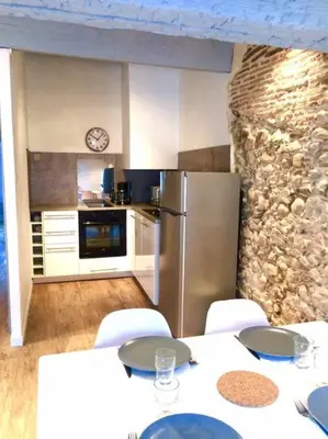 a kitchen with a table with chairs and a refrigerator at Au pied de la Cité in Carcassonne