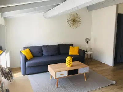 a living room with a blue couch and yellow pillows at Au pied de la Cité in Carcassonne