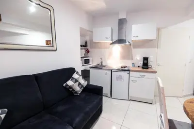 a living room with a black couch and a kitchen at Chambre Familiale du Couvent in Narbonne