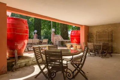 a patio with a table and chairs and red vases at Hôtel du Canal in Castelnaudary