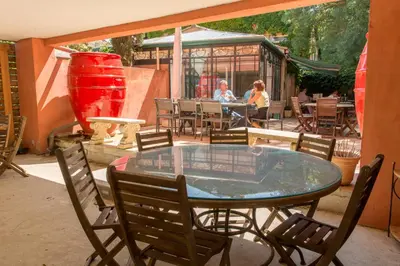 a glass table and chairs on a patio with people sitting at tables at Hôtel du Canal in Castelnaudary