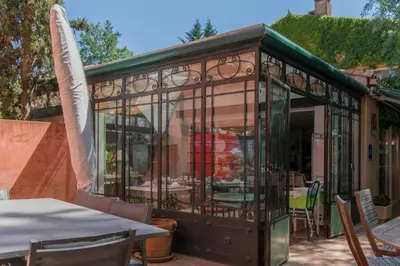 a glass house with a table and chairs in it at Hôtel du Canal in Castelnaudary