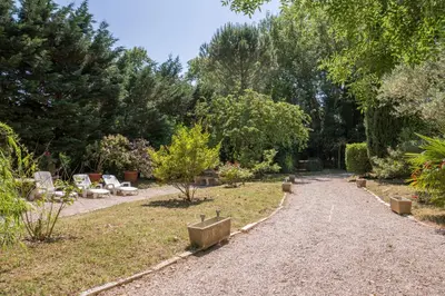 a path in a garden with chairs and trees at Hôtel du Canal in Castelnaudary