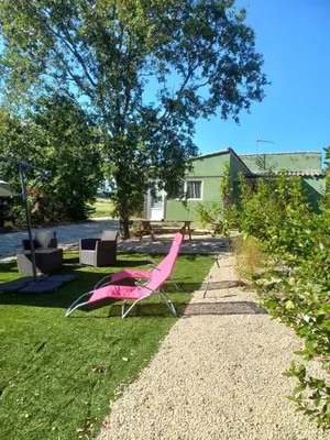 a pink chair sitting on the grass in a yard at gite tout confort in Montolieu
