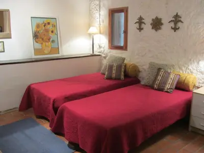 a bedroom with two beds with red sheets at L'Ecurie in Paziols
