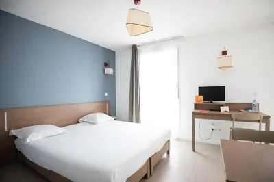 a bedroom with a bed and a desk and a television at Zenitude Hôtel-Résidences Narbonne Centre in Narbonne