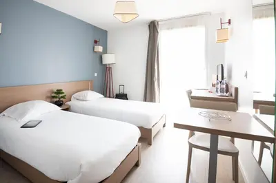 a hotel room with two beds and a table at Zenitude Hôtel-Résidences Narbonne Centre in Narbonne