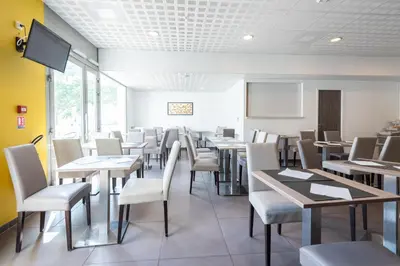 a dining room with tables and chairs and a tv at Zenitude Hôtel-Résidences Narbonne Centre in Narbonne