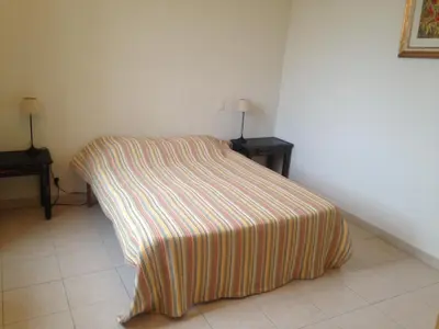a bed with a striped blanket in a room at La Ginelle - Appartement Guy in Airoux