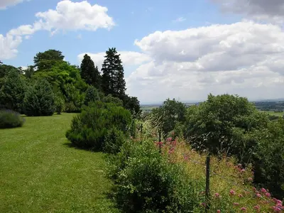 a garden with flowers and bushes on a hill at La Ginelle - Appartement Guy in Airoux
