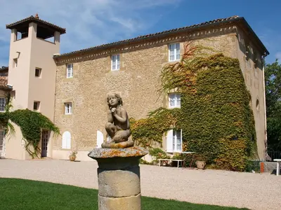 a statue of a little girl sitting on a fountain in front of a building at La Ginelle - Appartement Bocage in Airoux
