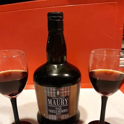 a bottle of wine sitting between two wine glasses at L'Amandier in Maury
