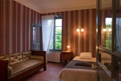 a bedroom with a bed and a couch and a window at Logis Hotel - Restaurant La Marbrerie in Caunes-Minervois