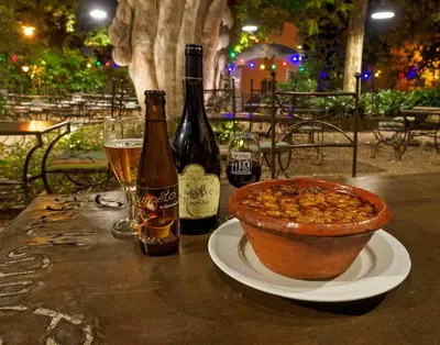 a table with two bottles of wine and a bowl of food at Logis Hotel - Restaurant La Marbrerie in Caunes-Minervois