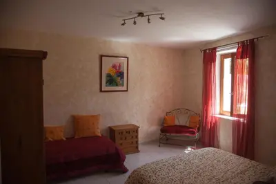 a bedroom with two beds and a window and a chair at LE CLOS DES COLVERTS in Campagne-sur-Aude