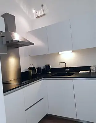 a kitchen with white cabinets and a sink at Les Suites du Saint Nazaire, vue panoramique sur la Cité Médiévale - Les Balcons de la Cité in Carcassonne