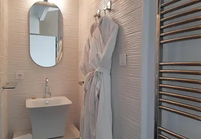 a white bathroom with a sink and a mirror at Les Suites du Saint Nazaire, vue panoramique sur la Cité Médiévale - Les Balcons de la Cité in Carcassonne