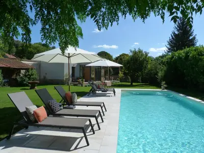 a swimming pool with lounge chairs and an umbrella at Maison Pigeonnier in Alet-les-Bains