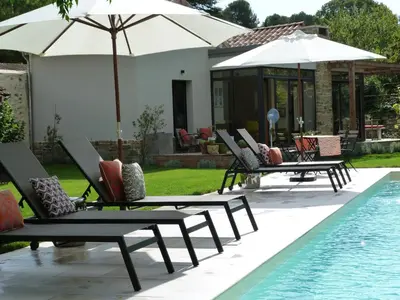 a group of lounge chairs with umbrellas next to a pool at Maison Pigeonnier in Alet-les-Bains