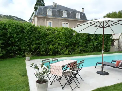 a table and chairs with an umbrella next to a pool at Maison Pigeonnier in Alet-les-Bains