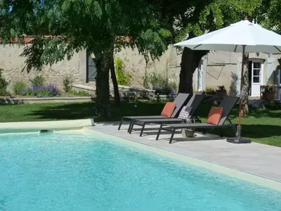 a pair of chairs and an umbrella next to a pool at Maison Pigeonnier in Alet-les-Bains