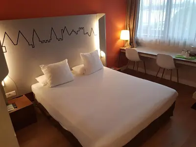 a bedroom with a large white bed with two pillows at Kyriad Carcassonne - Aéroport in Carcassonne