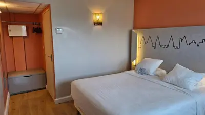 a bedroom with a white bed with a teddy bear on it at Kyriad Carcassonne - Aéroport in Carcassonne
