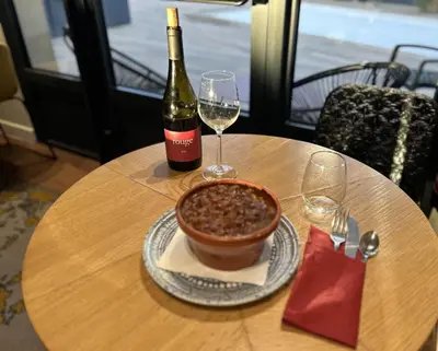 a table with a bottle of wine and a bowl of food at Kyriad Carcassonne - Aéroport in Carcassonne