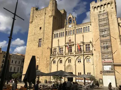 a large stone building with a clock tower at Aux 4 FONTAINES in Narbonne