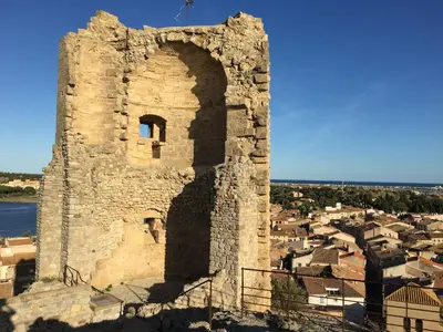 an old stone tower with a city in the background at Aux 4 FONTAINES in Narbonne