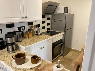 a kitchen with white cabinets and a stainless steel refrigerator at Aux 4 FONTAINES in Narbonne