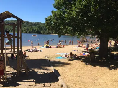 a group of people on the beach at a lake at Studio duplex 1 Lac des Montagnès in Mazamet