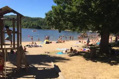 a group of people on the beach at a lake at Studio duplex 2 Lac des Montagnès in Mazamet
