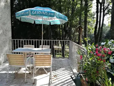a table and chairs under an umbrella on a patio at Studio duplex 2 Lac des Montagnès in Mazamet