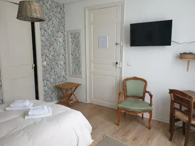 a bedroom with a bed and a chair and a flat screen tv at Chambres d'Hôtes et Gîtes- L'Abri sous Roche in Tautavel