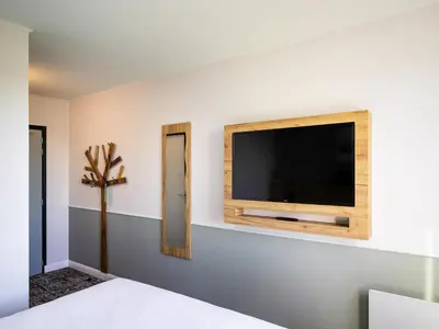 a bedroom with a flat screen tv on a wall at Greet Hôtel Castres Saix in Saix