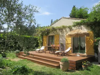a wooden deck with a table and chairs in a yard at KiOui in Rennes-les-Bains