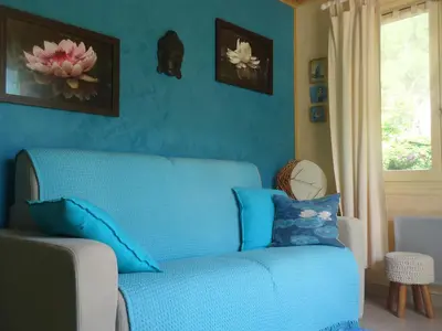 a blue couch in a living room with a window at KiOui in Rennes-les-Bains
