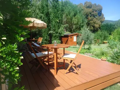 a wooden deck with a table and chairs and an umbrella at KiOui in Rennes-les-Bains