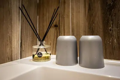 two white candles and a bottle of perfume on a shelf at 45BB in Carcassonne