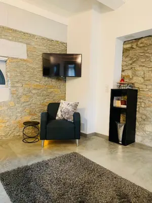 a living room with a chair and a tv on a wall at 45BB Apartment in Carcassonne