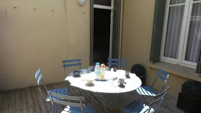 a white table with blue chairs and a table with food on it at spacieux logement face à la Cité Médievale in Carcassonne