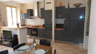 a kitchen with black cabinets and a table with chairs at spacieux logement face à la Cité Médievale in Carcassonne