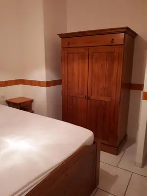 a bedroom with a wooden cabinet and a bed at Méditerranée in Sigean
