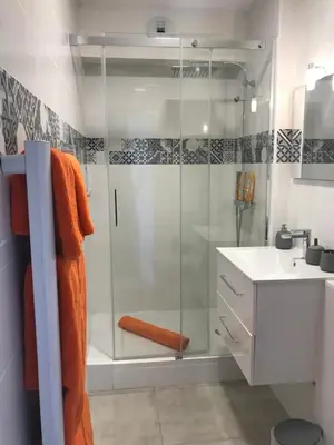 a bathroom with a glass shower and a sink at LE MONICA in Narbonne
