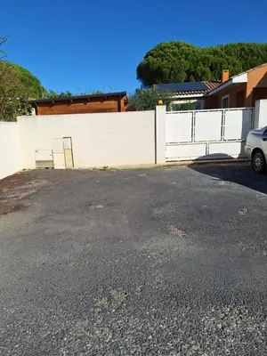a parking lot next to a white fence at Studio Meublé non fumeur in Narbonne