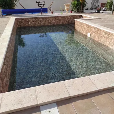 a swimming pool with a stone retaining wall and a swimming poolvisor at Studio Meublé non fumeur in Narbonne
