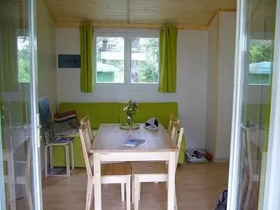a dining room with a table and chairs and a window at Chalet et mobil homes dans la montagne au Camping les Sapins in Camurac