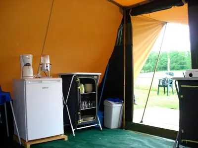a tent with a refrigerator and a door to a patio at Chalet et mobil homes dans la montagne au Camping les Sapins in Camurac