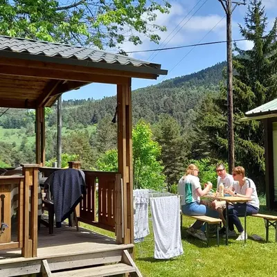 a group of people sitting at a table on a deck at Chalet et mobil homes dans la montagne au Camping les Sapins in Camurac
